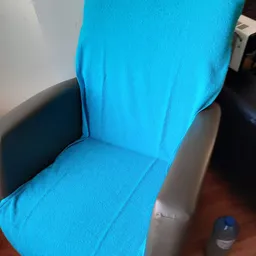 Close-up van een blauwe stoelzitting en rugleuning met zwarte armleuning