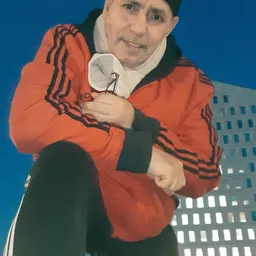 Close-up van een rood Adidas-jack met zwarte strepen, gedragen door een persoon tegen blauwe achtergrond