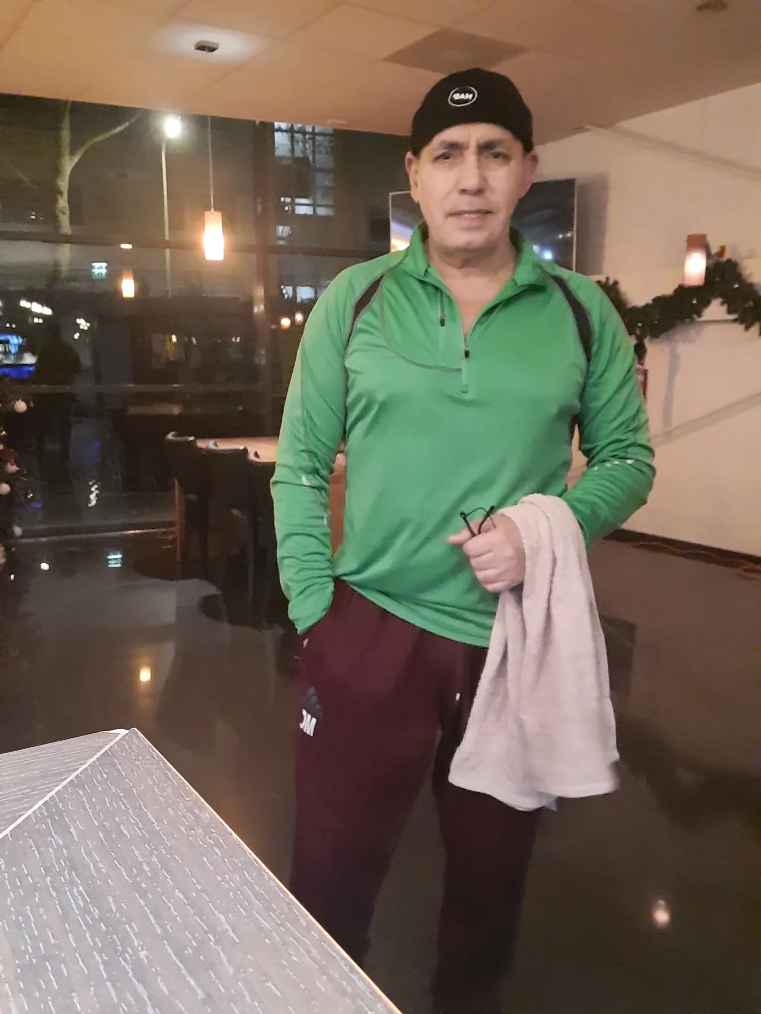 Persoon in groen sportshirt en bordeauxrode broek in winkelinterieur
