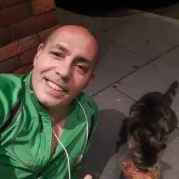 Man in groen jack glimlachend naar camera, mogelijk personeelslid of vrijwilliger