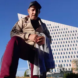 Man in vrijetijdskleding poseeert voor een modern kantoorgebouw