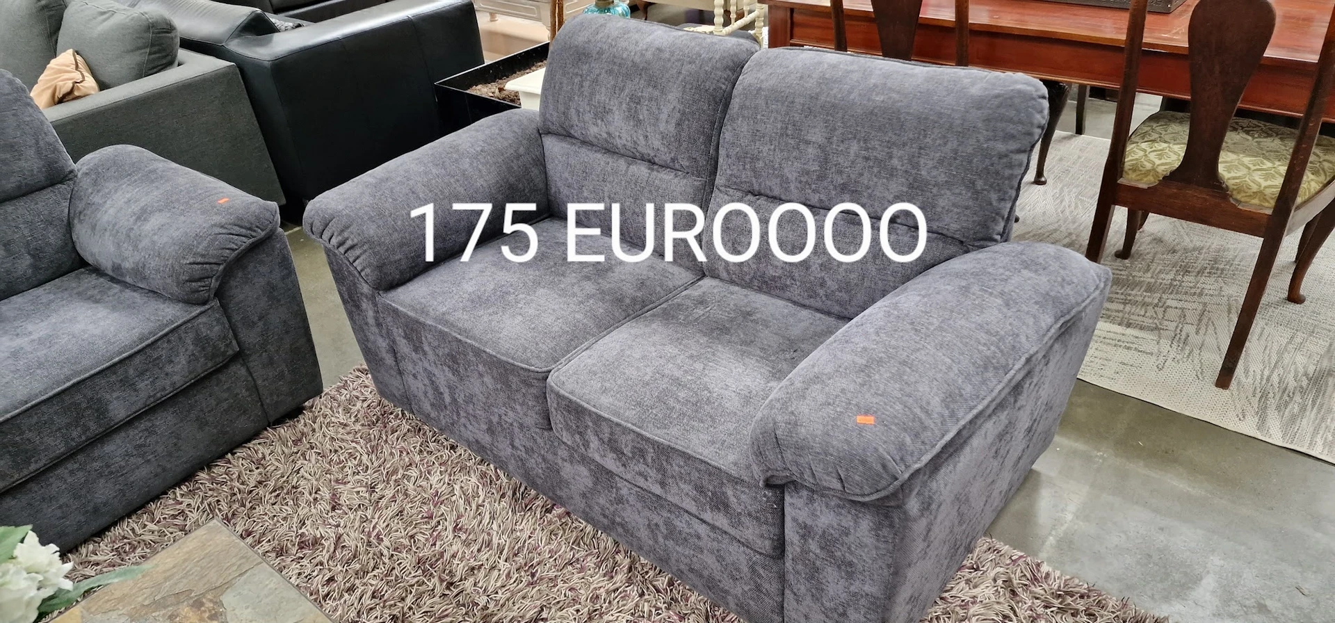 Grijze tweedehands stoelgroep met twee zitplaatsen op een vloerkleed in de kringloopwinkel