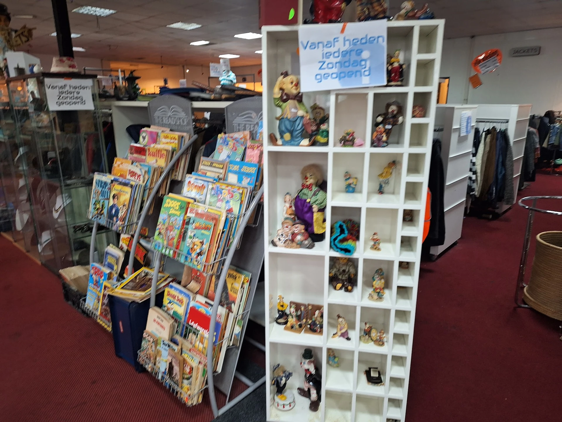 Winkelinterieur met displaykasten en rekken vol tweedehands spullen, boeken en verzamelobjecten
