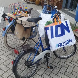 Twee tweewielers met tassen en een wit spandoek met 'TION' en 'ACTION' opgesteld buiten op straat
