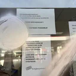 Aankondiging op raam over meer mogelijkheden en openingstijde van winkel