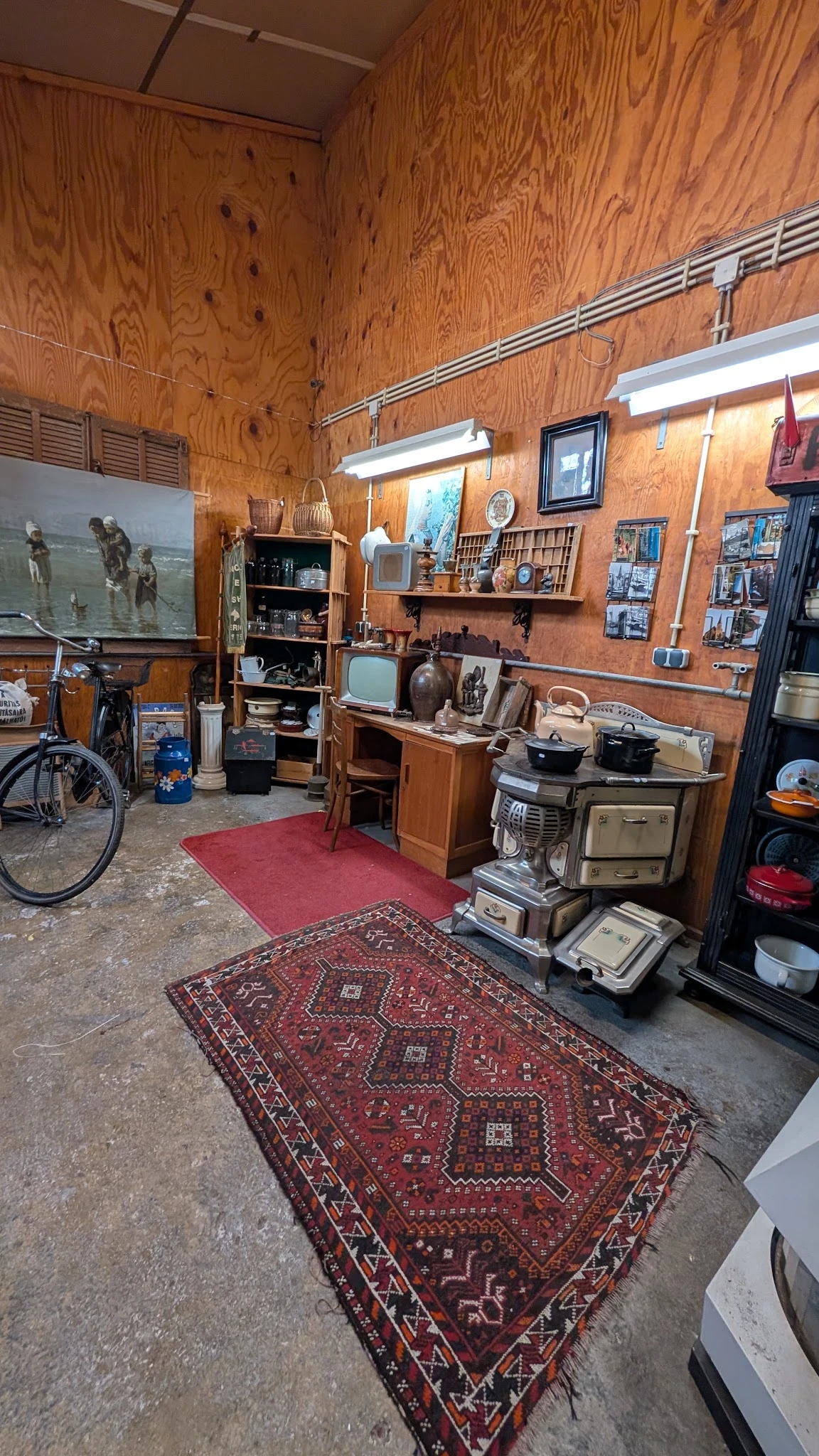 Winkelvloer met vintage huishoudapparatuur, meubels, televisies en decoratieartikelen op houten planken tegen houten wanden