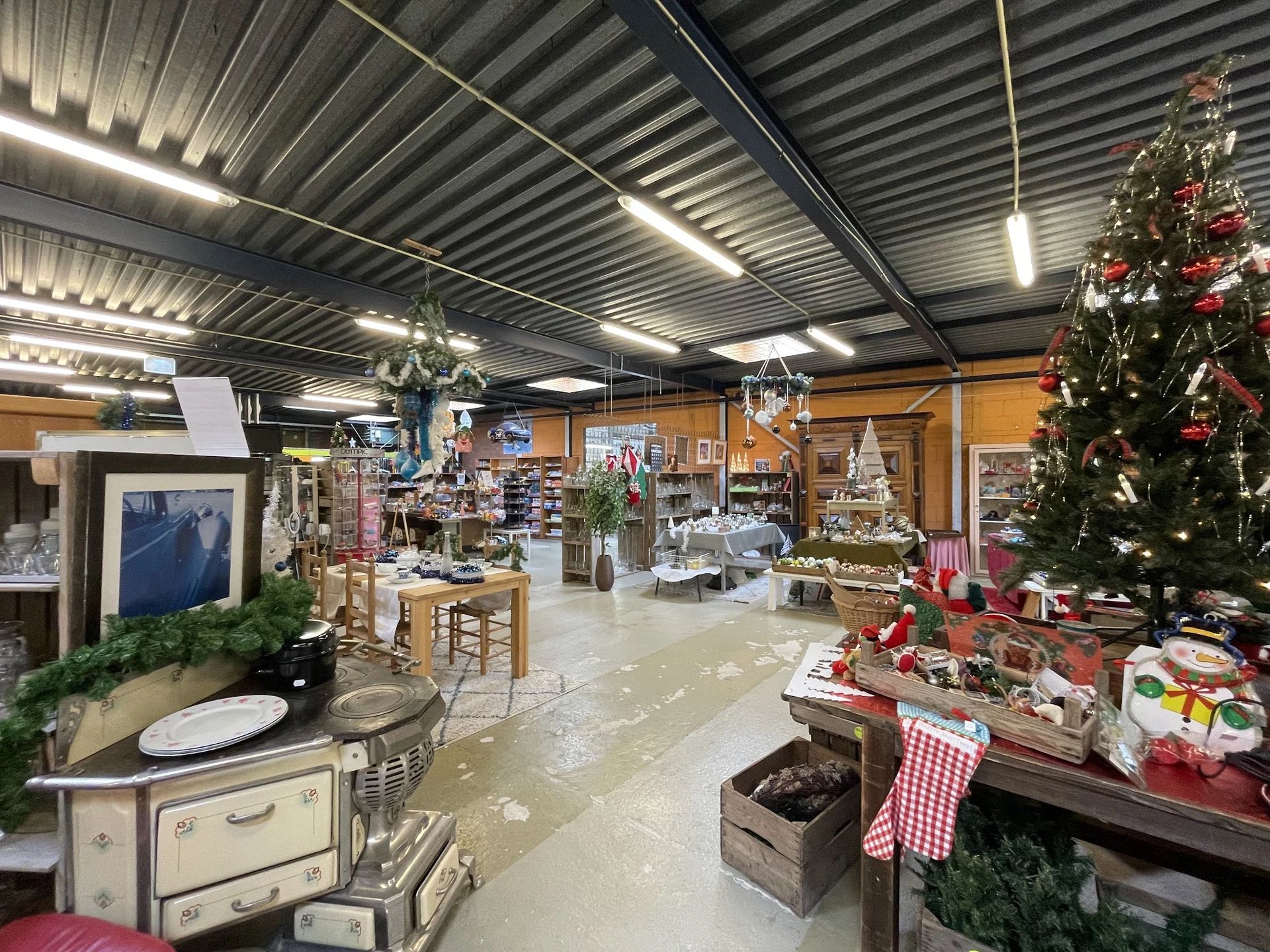 Binnenkant kringloopwinkel met verschillende afdelingen, kerstversiering en aangeboden spullen