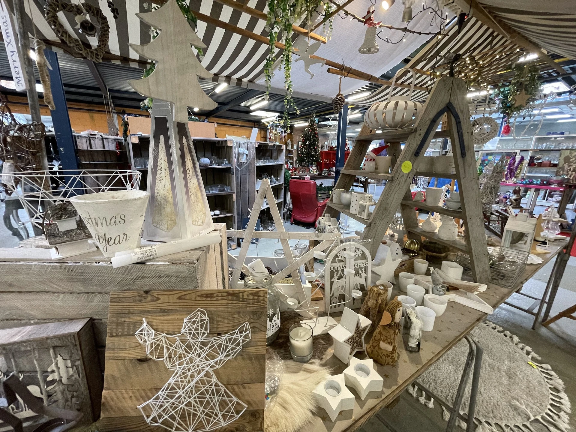 Winkelbinnenkant met stellingen, decoratieve items, houten frames en witte kandelaars op tafels, sfeervolle inrichting met ha