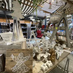 Winkelbinnenkant met stellingen, decoratieve items, houten frames en witte kandelaars op tafels, sfeervolle inrichting met ha