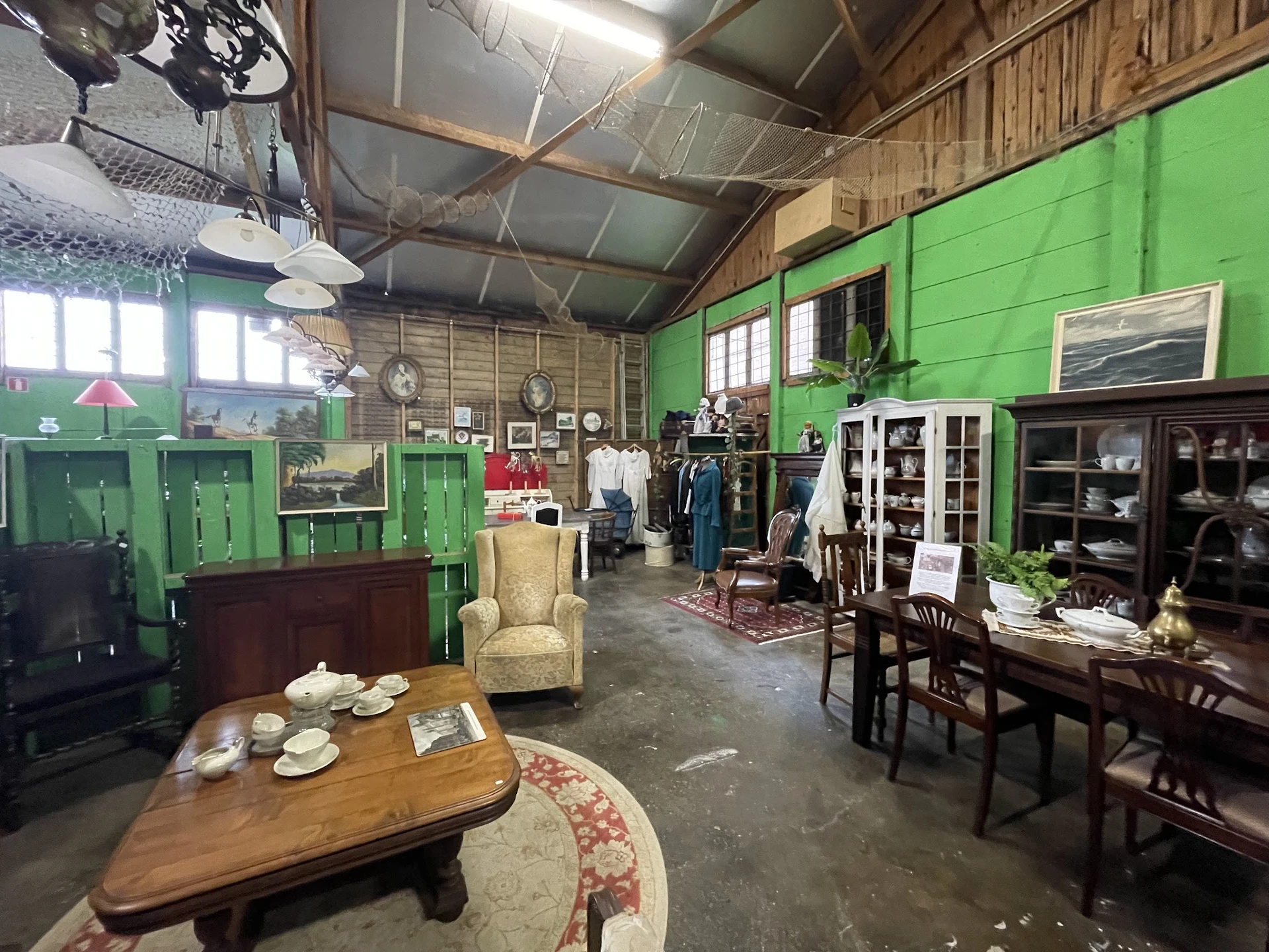 Winkelinterieur met groene wanden, diverse meubels, kasten en huishoudartikelen uitgestald