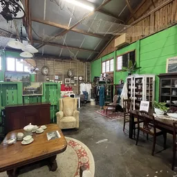 Winkelinterieur met groene wanden, diverse meubels, kasten en huishoudartikelen uitgestald