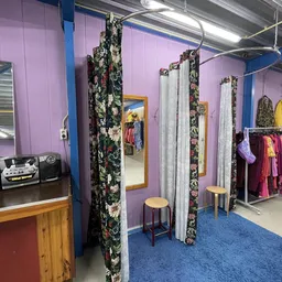 Winkelvloer met paskamers, kledingrekken en blauwe vloerbedekking onder paarse en blauwe verlichting