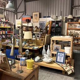 Winkelvloer vol met tweedehands meubels, lampen, servies, boeken en decoratieartikelen in verschillende hoeken