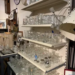 Glazen en drinkglazen op witte stellingen in een kringloopwinkel