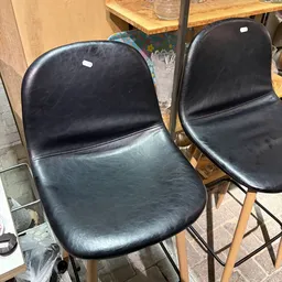 Twee zwarte kunststof stoelen met houten poten, close-up van zitting en rugleuning