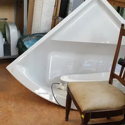 Witte hoekbadkuip en houten stoel met zitting in de winkel