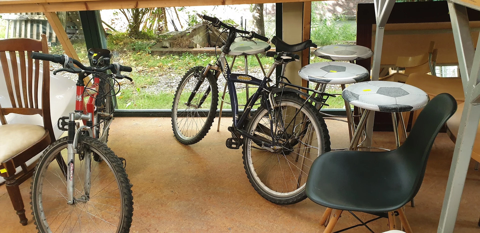 Fietsen en stoelen in een overdekt winkelgedeelte met glazen deuren naar buiten