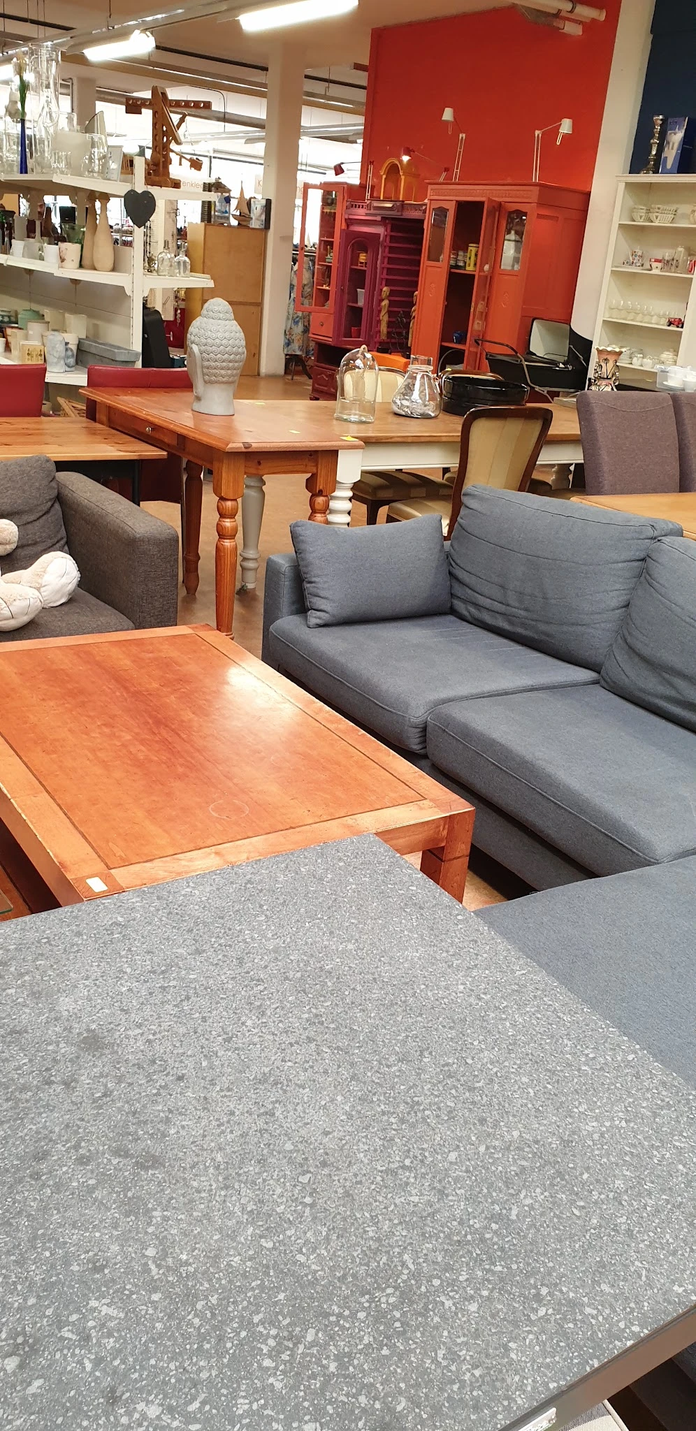 Grijze stoffebank met kussens en houten salontafel in meubelafdeling