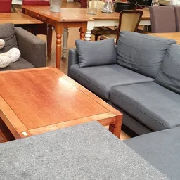 Grijze stoffebank met kussens en houten salontafel in meubelafdeling