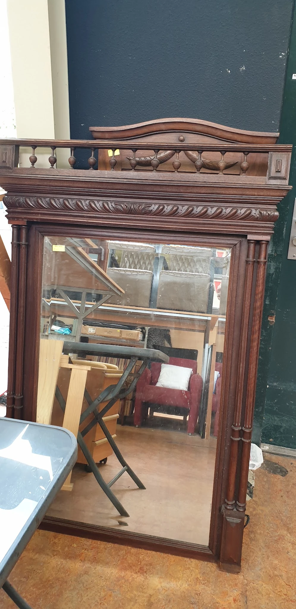 Binnenaanzicht van kringloopwinkel met houten frame, stellingen en diverse gebruikte meubels en spullen
