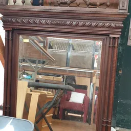 Binnenaanzicht van kringloopwinkel met houten frame, stellingen en diverse gebruikte meubels en spullen