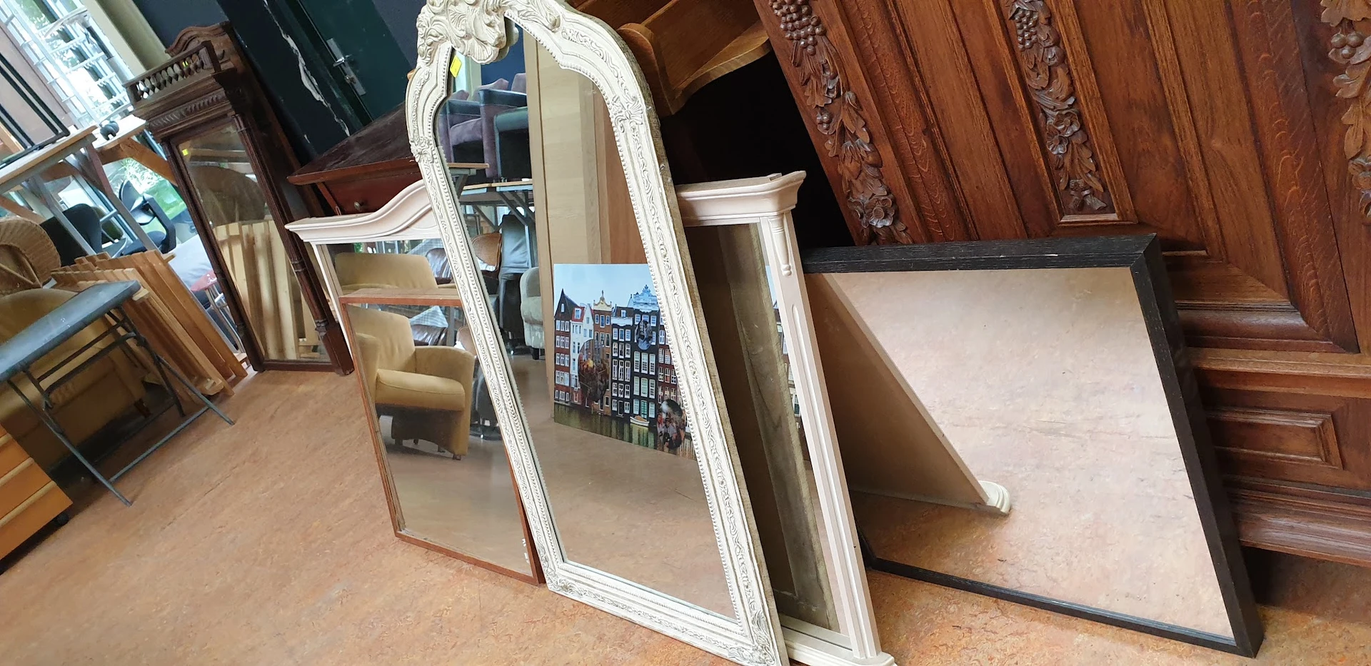 Witte spiegel met decoratieve lijst naast houten meubels in de winkel
