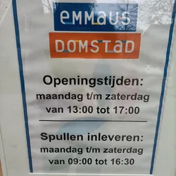 Openingstijden en inleveringsregels van een kringloopwinkel op een papieren bord