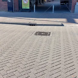 Straatbestrating met drains en inlaten, gedeeltelijk in schaduw