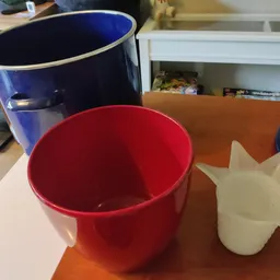 Twee plastic emmers (blauw en rood) en een wit plastic object op een tafel