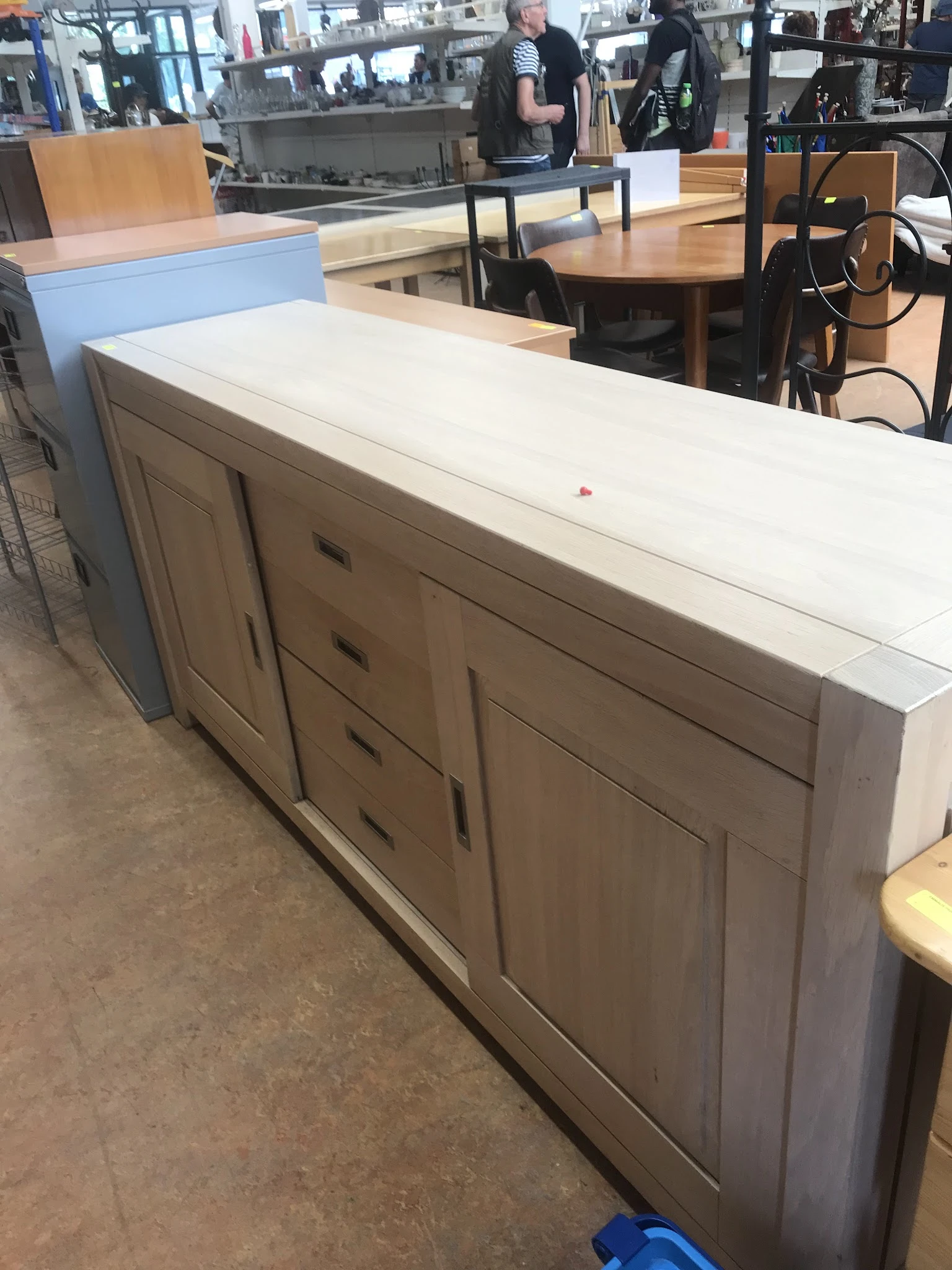 Witte sideboard met grijsbeige deuren en laden, op betonnen vloer in een winkelpand