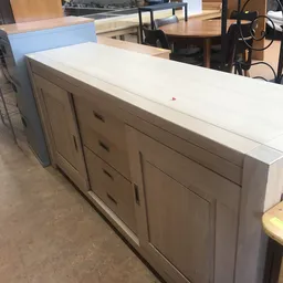 Witte sideboard met grijsbeige deuren en laden, op betonnen vloer in een winkelpand