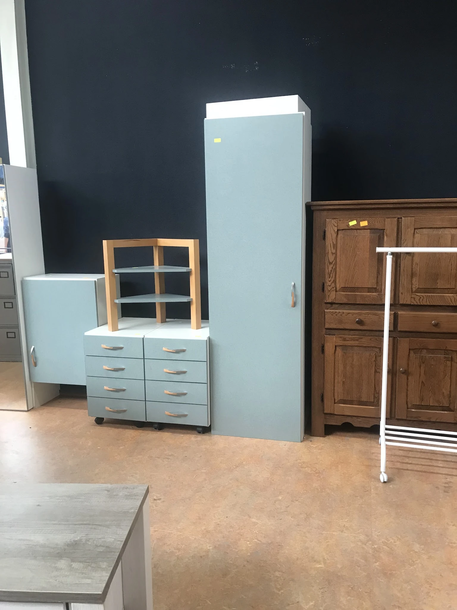 Tweedehands meubels in de winkel: een lichtblauwe ladekast met houten raamkozijn bovenop, een grote lichtblauwe kast en houte