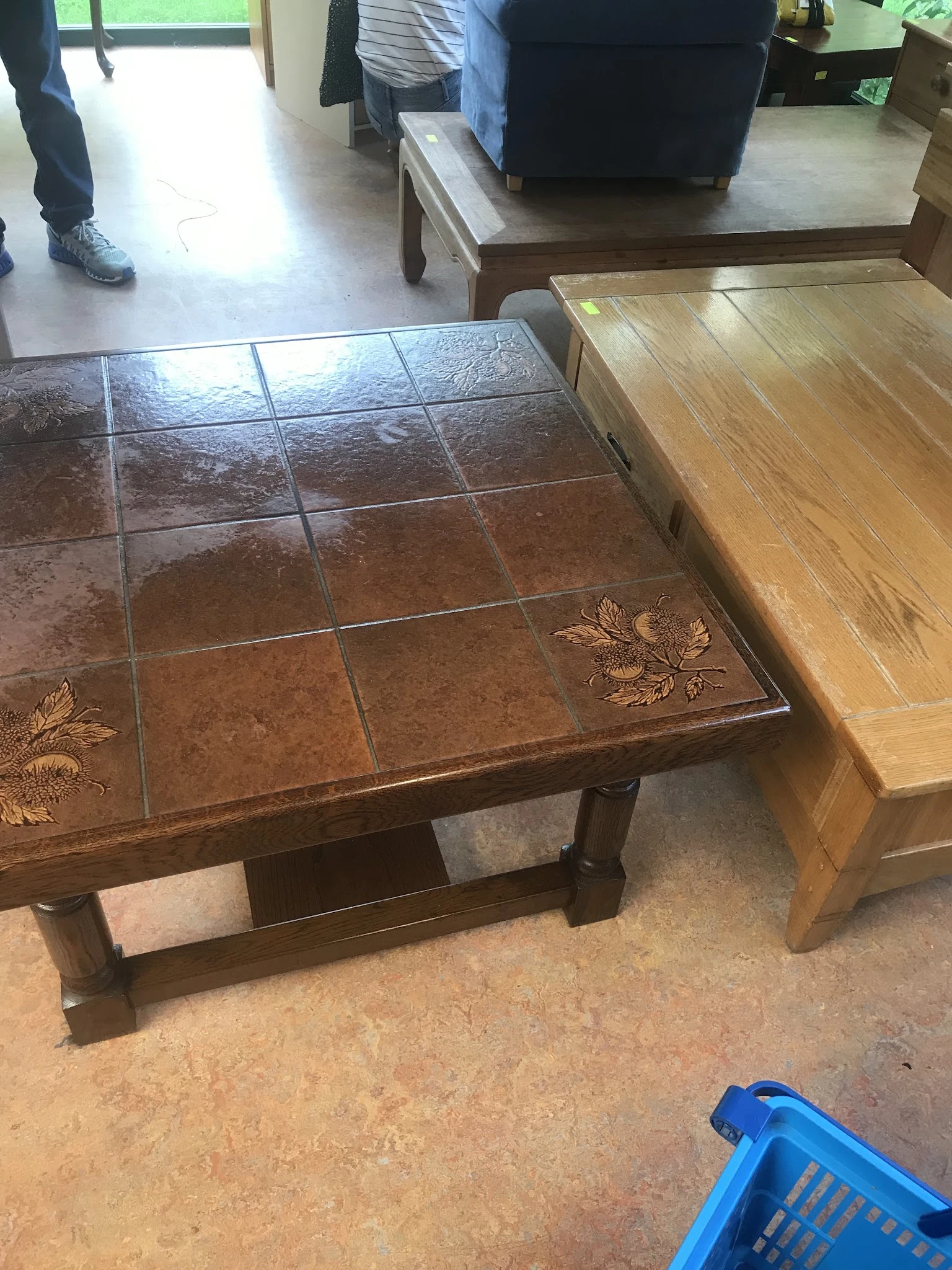 Bruine salontafel met tegeltop en decoratieve details naast houten meubel
