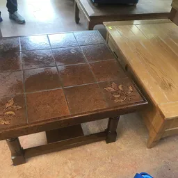 Bruine salontafel met tegeltop en decoratieve details naast houten meubel