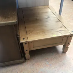 Houten tafel of werkbank met poten en donker blad, tegen muur en vloer