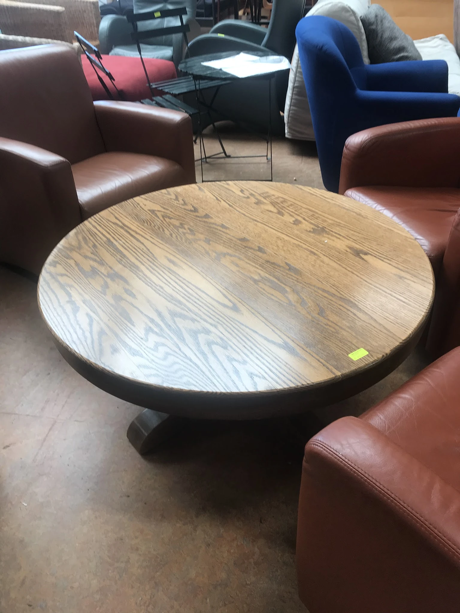 Ronde houten tafel met zwarte voet tussen bruine leren zitmeubels