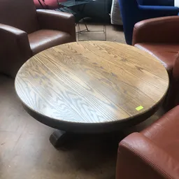 Ronde houten tafel met zwarte voet tussen bruine leren zitmeubels