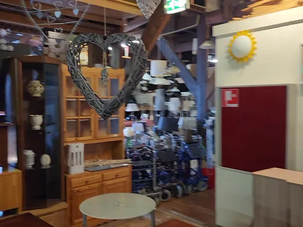 Winkelvloer met houten meubels, stellingen en diverse spullen, deels onscherp
