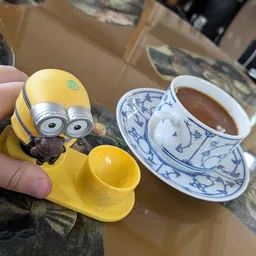 Minion-speelgoedfiguur en blauw-wit porseleinenkopje met thee