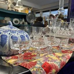 Blauw-wit porseleinen theepot en kristallen glazen op een kleurig tafelkleed in de winkel