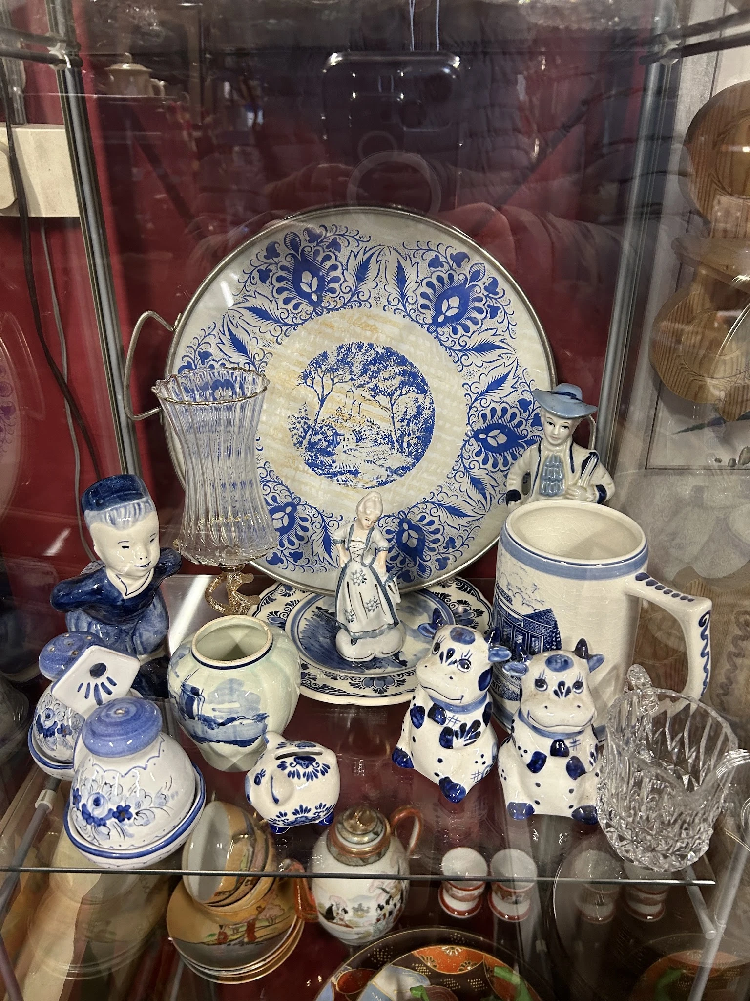 Vitrinekast met blauw-wit porselein: decoratief bord, beelden, kannen, vazen en ander serviesgoed