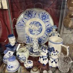 Vitrinekast met blauw-wit porselein: decoratief bord, beelden, kannen, vazen en ander serviesgoed