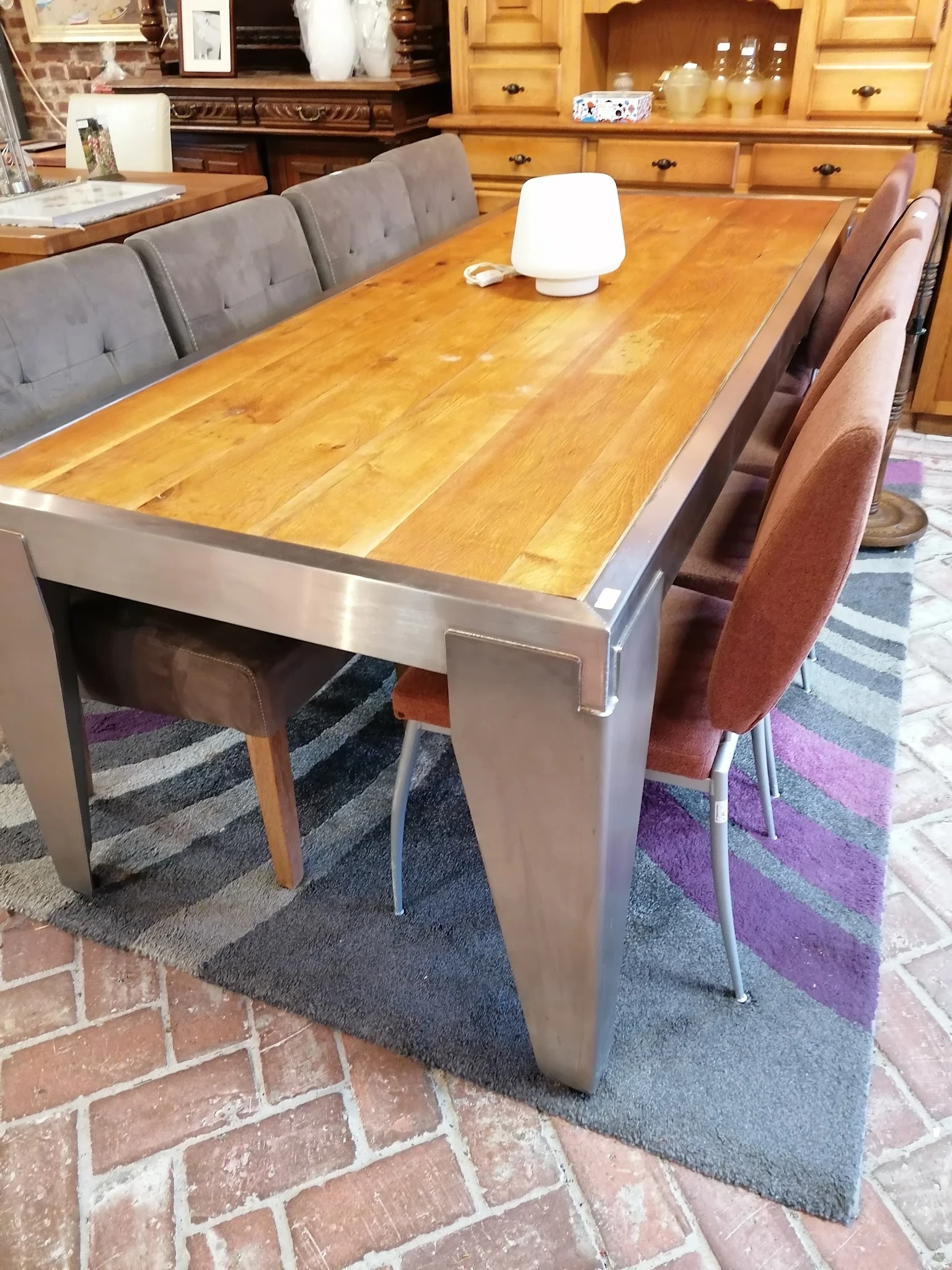 Houten eettafel met stalen frame en bruine stoelen op een paars gestreept vloerkleed
