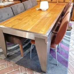 Houten eettafel met stalen frame en bruine stoelen op een paars gestreept vloerkleed