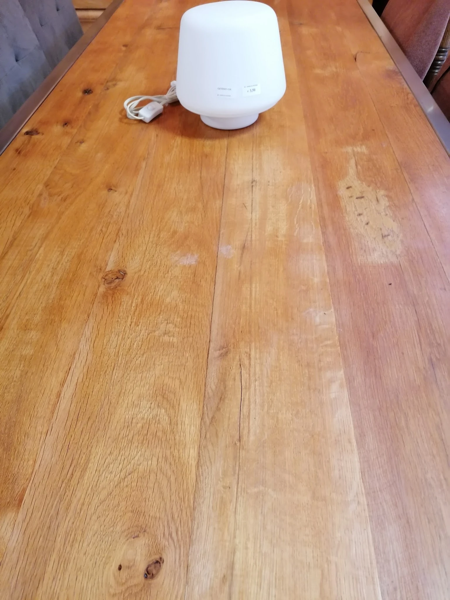 Houten vloer met planken in verschillende kleurtonen, enkele vlekken en sporen van slijtage zichtbaar