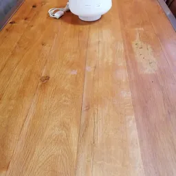 Houten vloer met planken in verschillende kleurtonen, enkele vlekken en sporen van slijtage zichtbaar