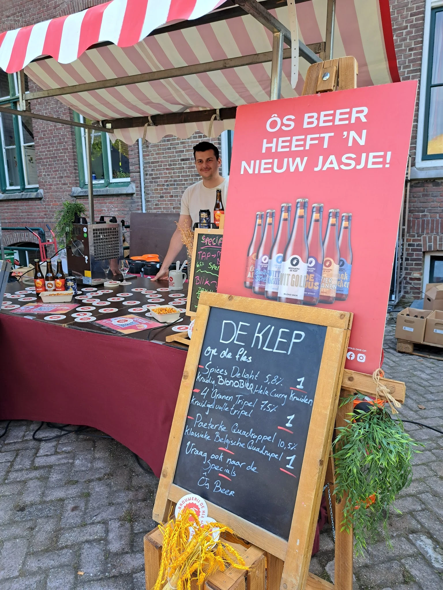 Verkoopstand met dranken en een krijtbord met menukaart 'De Klep' met prijzen