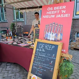 Verkoopstand met dranken en een krijtbord met menukaart 'De Klep' met prijzen