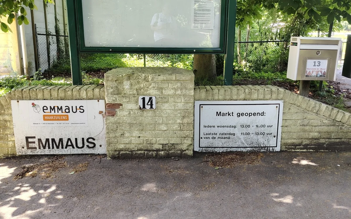 Voorgevel van kringloopwinkel Emmaus met huisnummer 14, openingstijden en informatiekasten