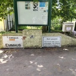 Voorgevel van kringloopwinkel Emmaus met huisnummer 14, openingstijden en informatiekasten
